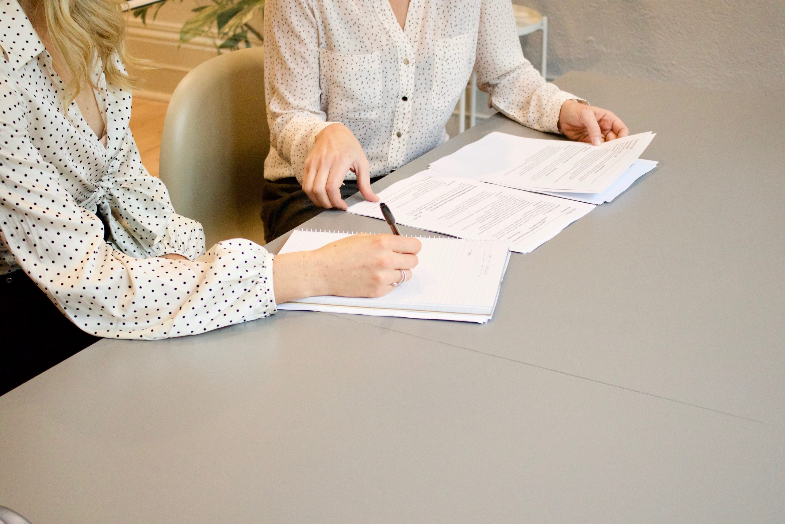 Two women sitting at a desk together, filling out paperwork